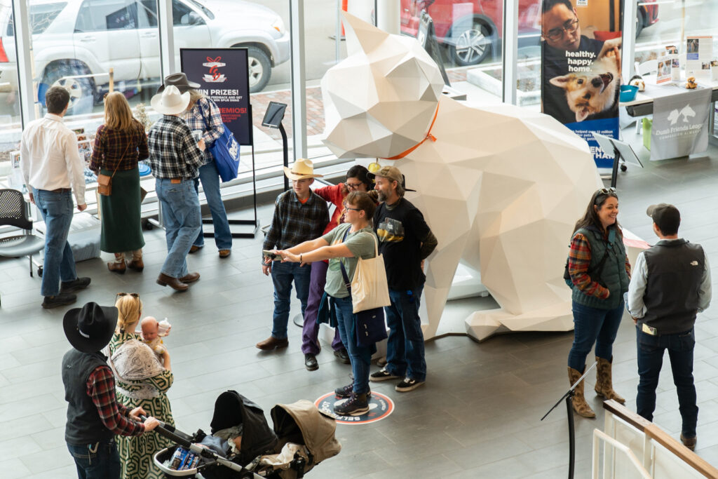 A group takes a selfie in front of a large white cat statue.