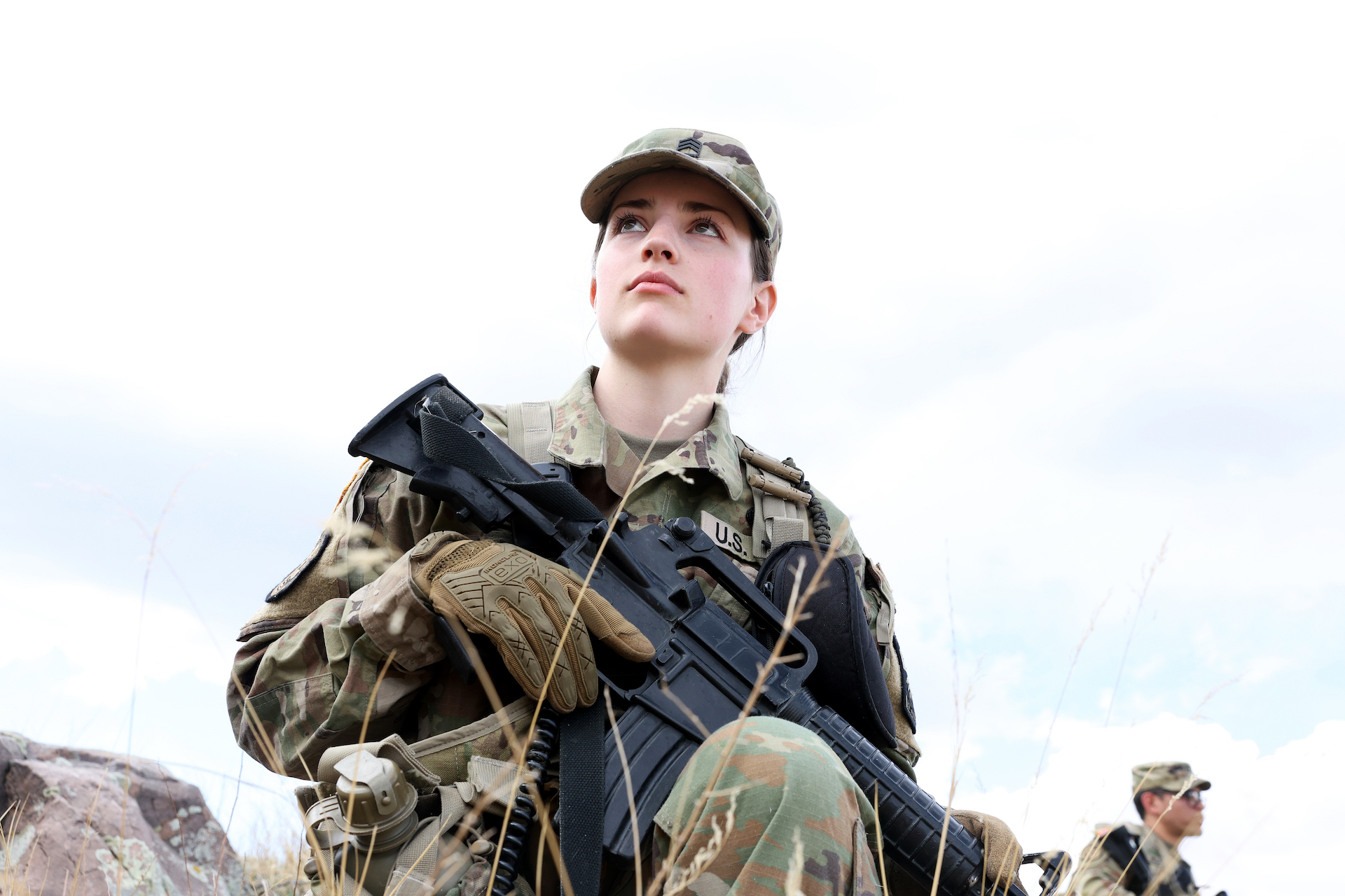 Ashley Magee in camo, holding a replica weapon.